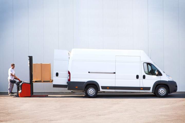 Un utilitaire blanc garé devant un bâtiment commercial, symbolisant le transport professionnel et la logistique urbaine.